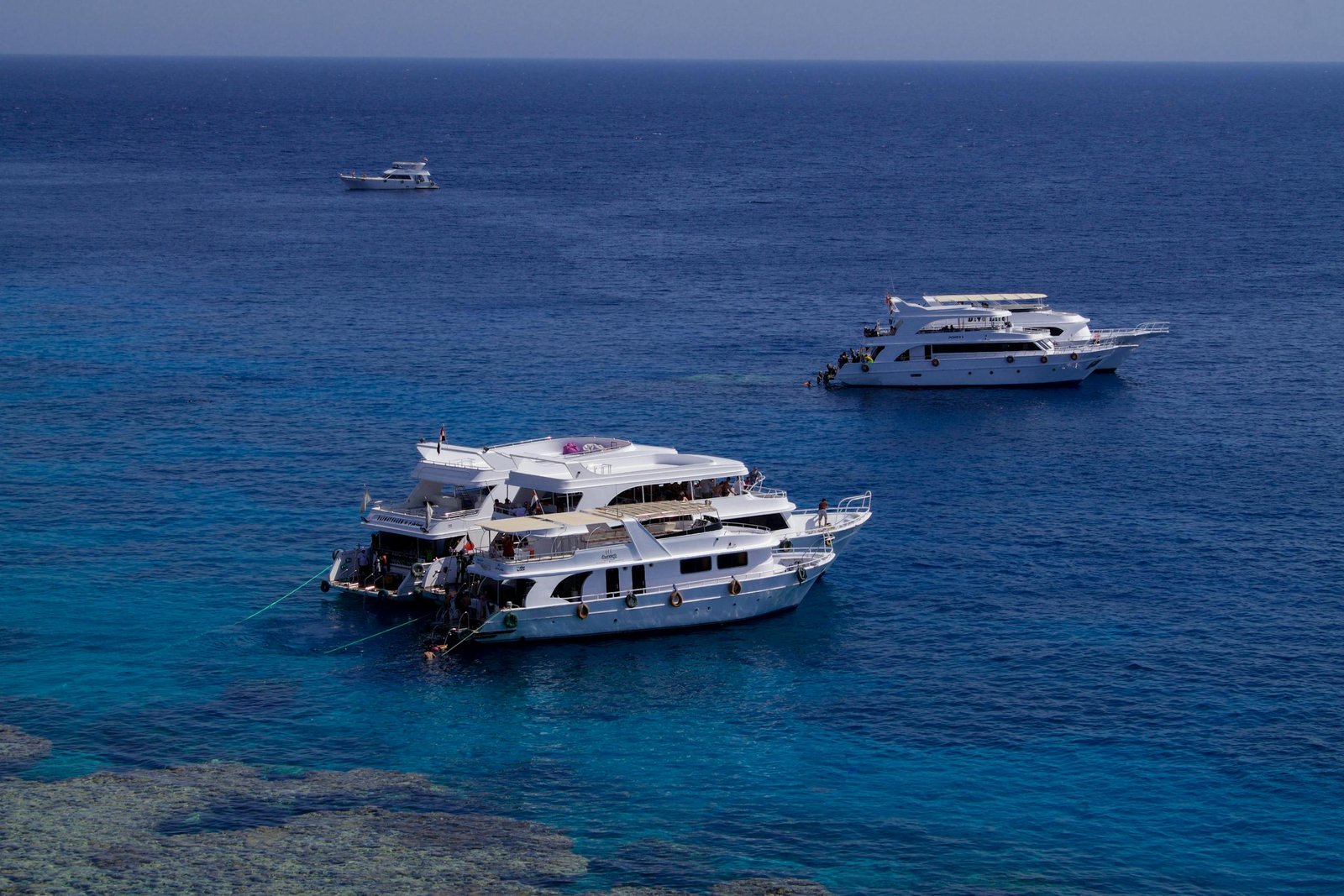 Luxury yachts cruising in the clear blue waters of Sharm El-Sheikh, Egypt, under a bright sky.